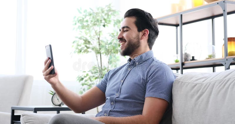 Young man video chatting using mobile phone at home stock footage