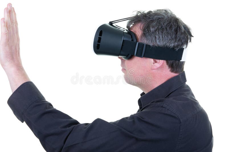 Young man with VR glasses touching imaginary interface indoors stock images