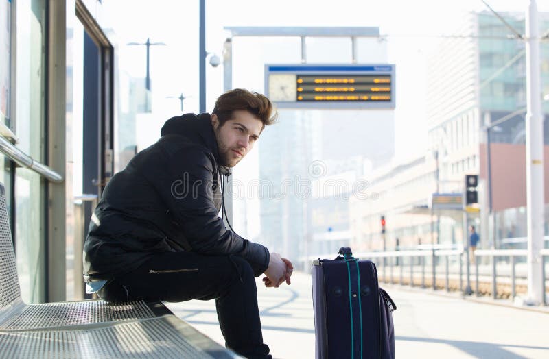 Young man waiting for train with suitcase travel bag