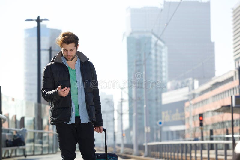 Young man walking with bag and mobile phone in the city