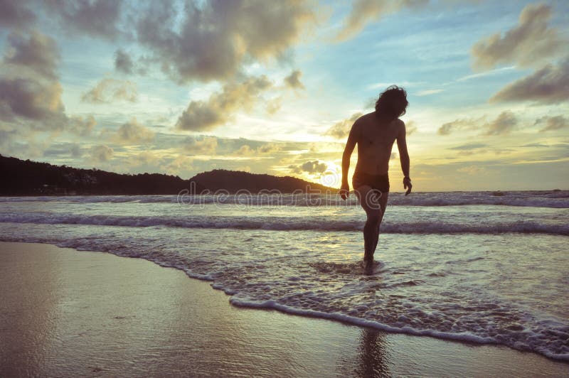 Young man walking on beach when sunset