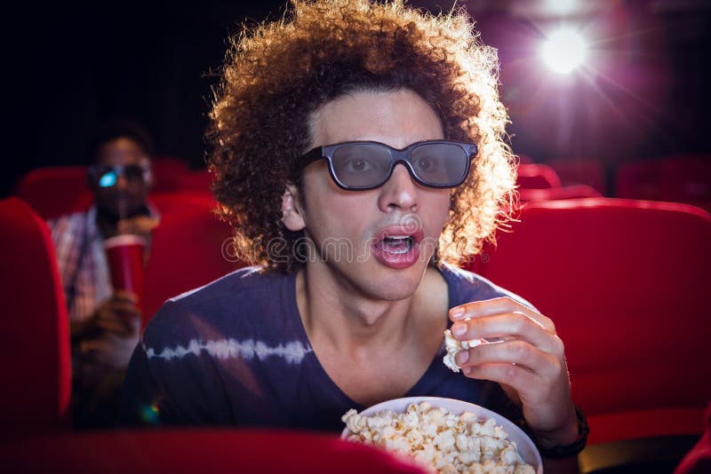 young-man-watching-d-film-eating-popcorn-cinema-53082317.jpg