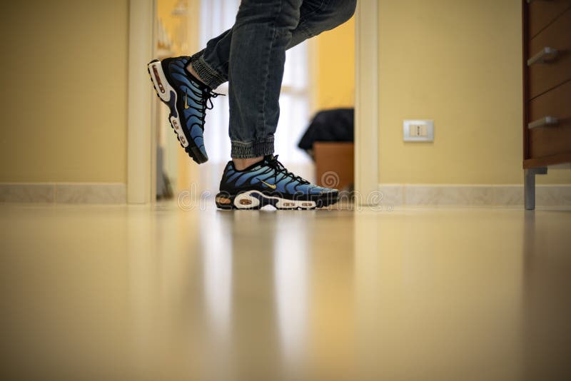 Young man wearing Nike Air Max Plus TN Hyperblue shoes at home