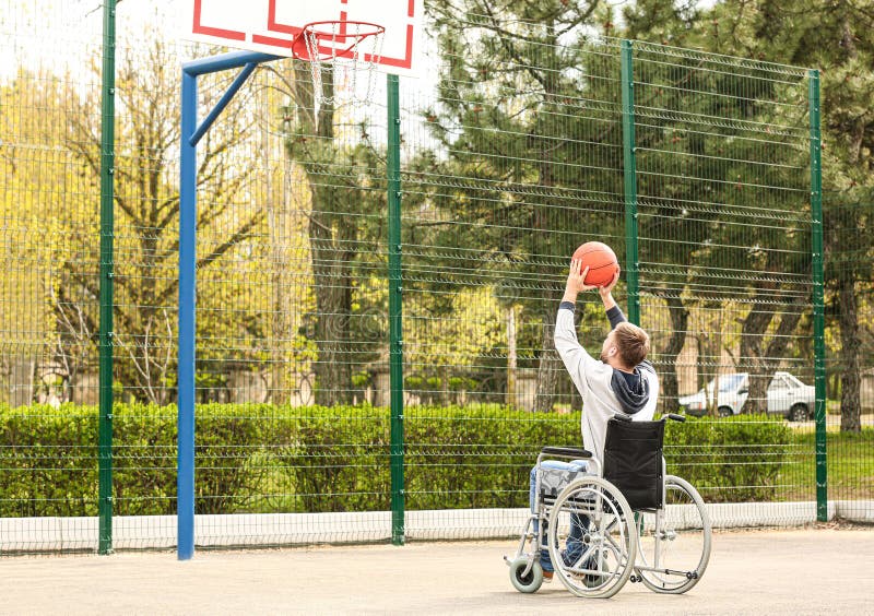 Young man in wheelchair playing basketball on ground royalty free stock photography Young man in wheelchair playing basketball on ground royalty free stock photography