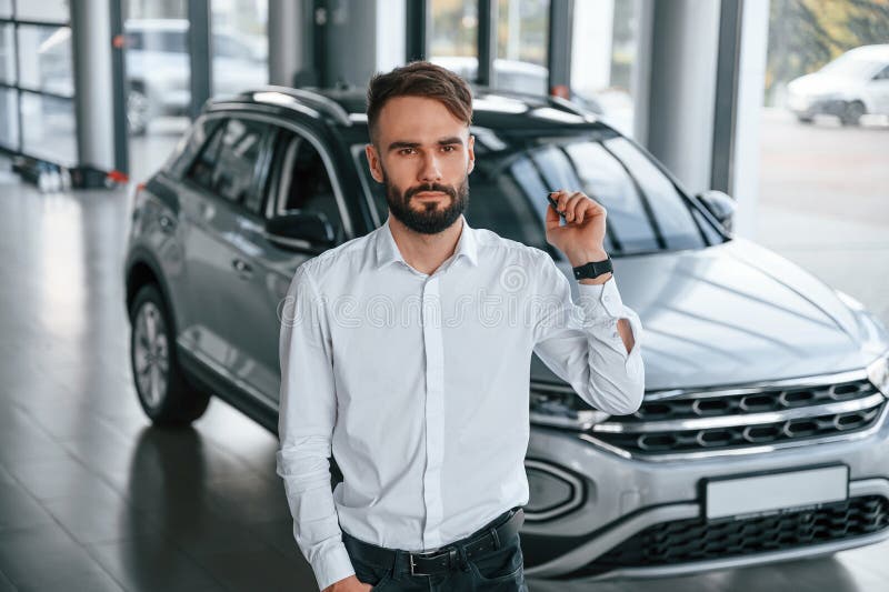 Young Man in White Clothes is in the Car Dealership Stock Photo Image