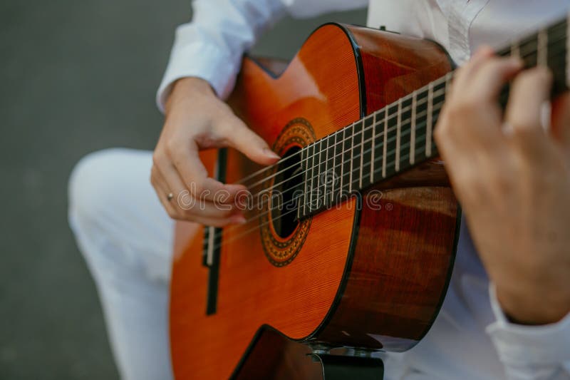 Young man in white playing classical guitar stock photography