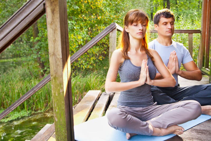 Young man and woman doing yoga in garden