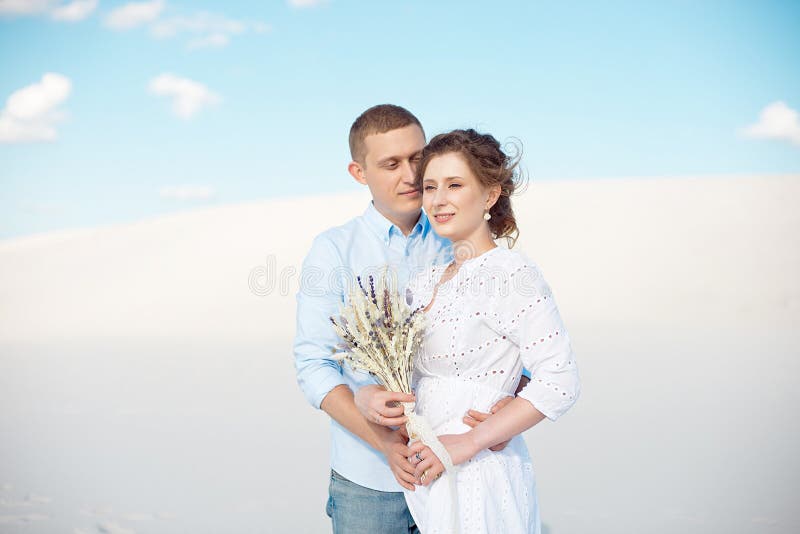 Young man and woman hugging on a background of white sand, dunes. Love story in the void. royalty free stock image Young man and woman hugging on a background of white sand, dunes. Love story in the void. royalty free stock image