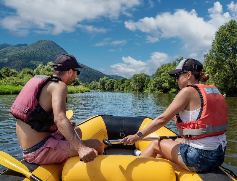 Young man and woman paddling in inflatable raft on Slovak mountain river Orava