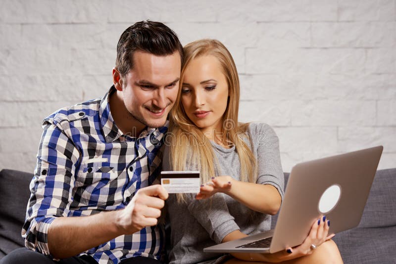Young man and woman are sitting on the couch and they are shopping online.