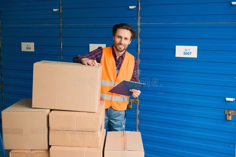 Waistup of Guy in Work Clothes with Boxes into Warehouse with Self Storage Unit Stock Image
