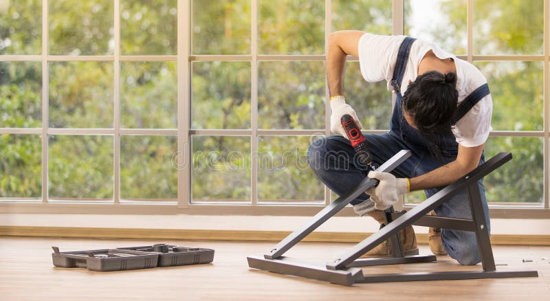 Young man working as handyman, assembling wood table with equipments, concept for home diy and self service.in the office. Young man working as handyman, assembling wood table with equipments, concept for home diy and self service.in the office.