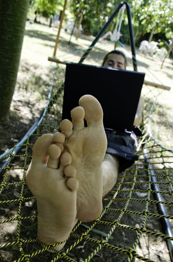 Young man working on his laptop in hammock