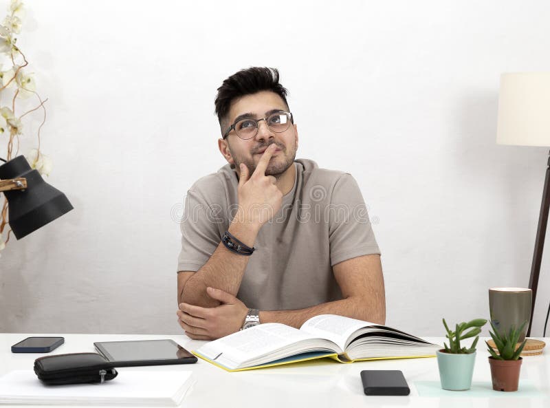 Young Man Working and Looks Thoughtful in His Home Office.education