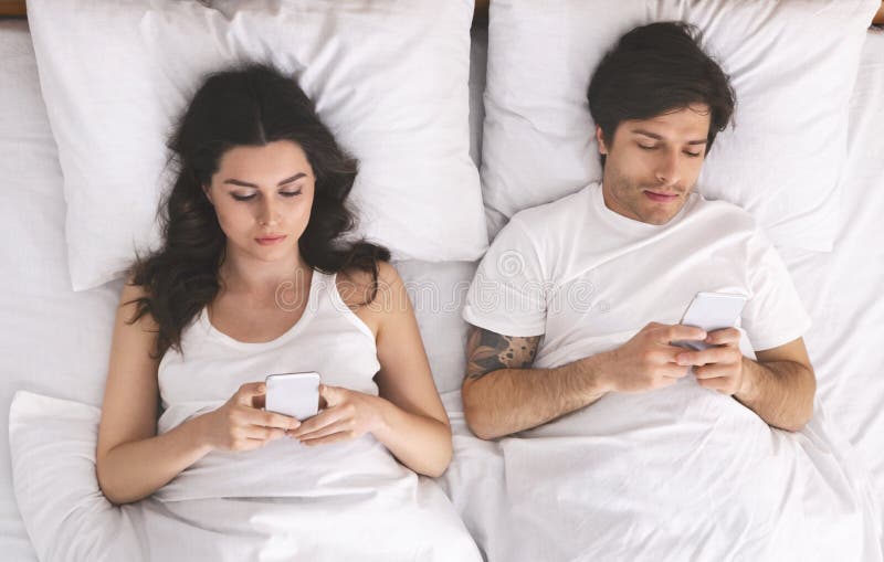 Young Married  Couple  Lying On Bed  And Using Laptop Stock 