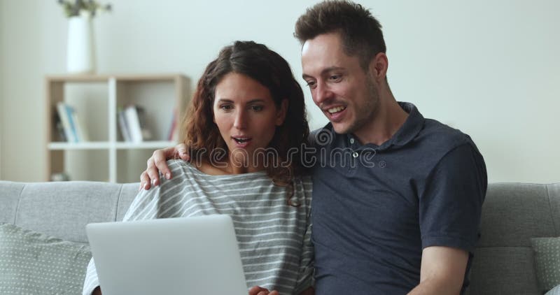 Young married couple using laptop on home couch together