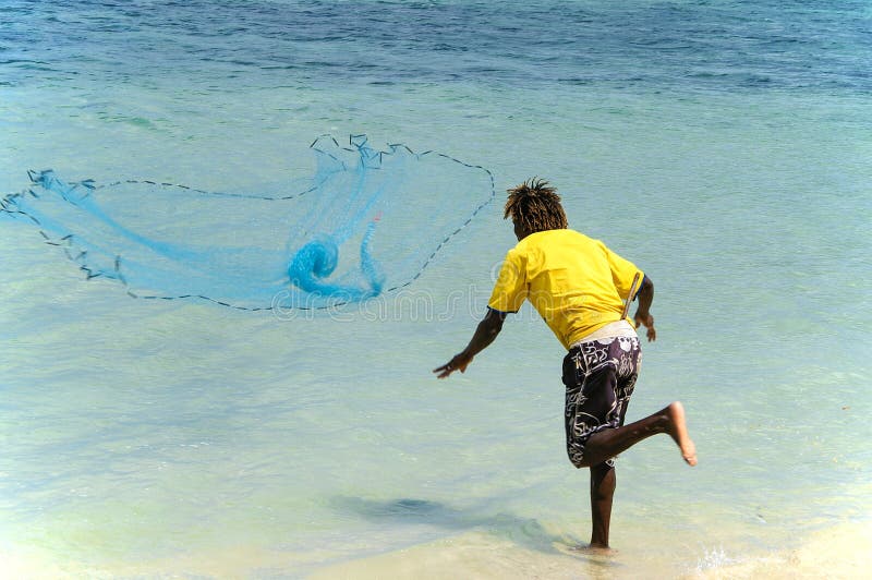 Young Mauritian Man on the Beach Throws Out a Net To Fish Editorial