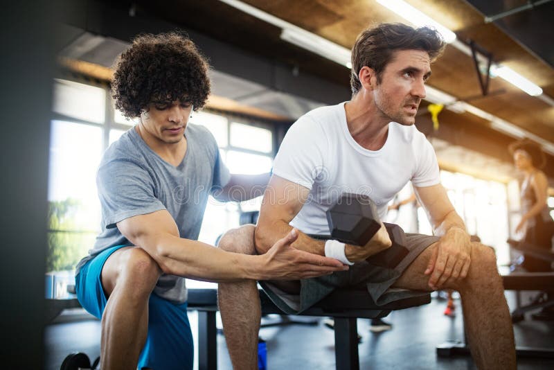 Young Fit Man Doing Workout with a Personal Trainer. Stock Image