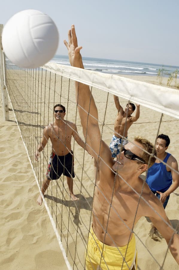 Young Men Playing Volleyball On Beach