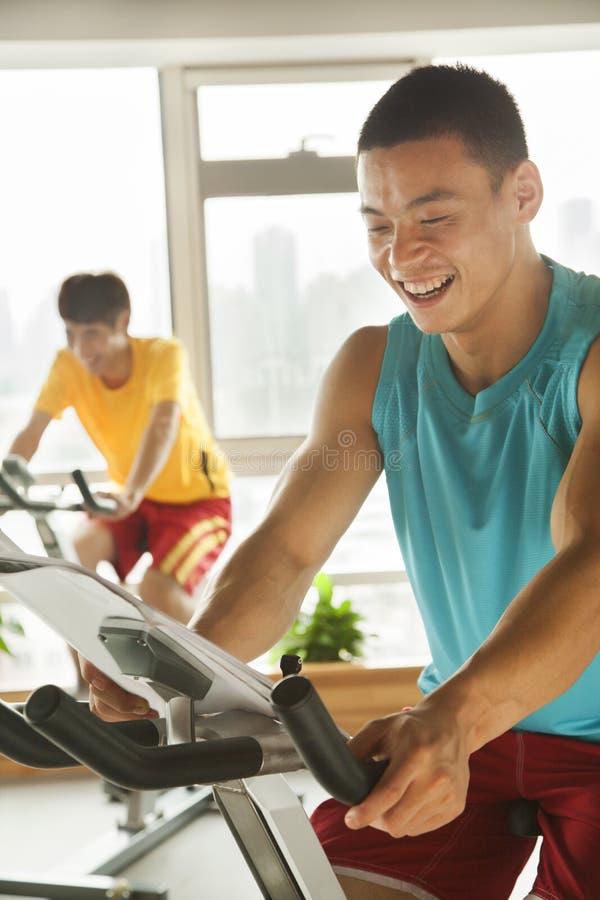 Young Men on Stationary Bikes Exercising in the Gym Stock Image Image
