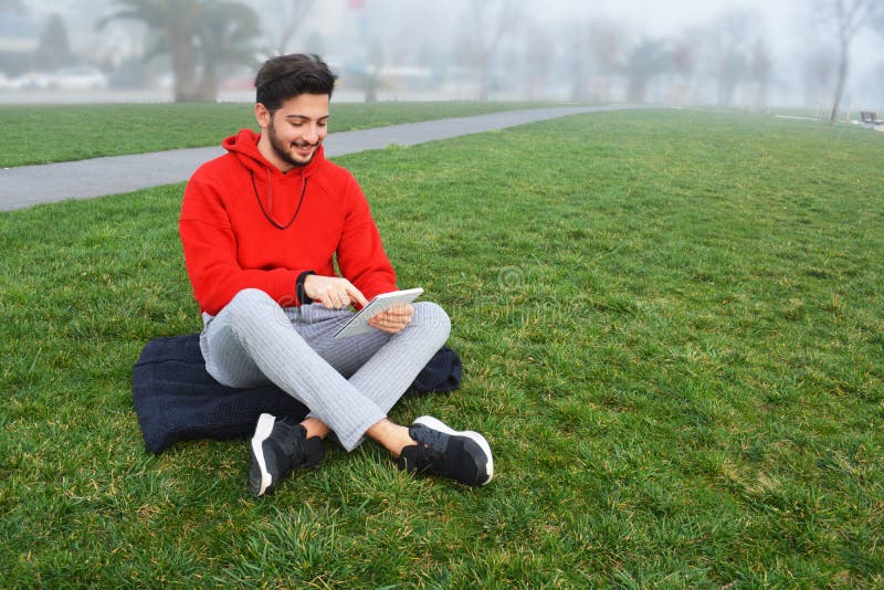 Young men using digital tablet in public park royalty free stock photos Young men using digital tablet in public park royalty free stock photos