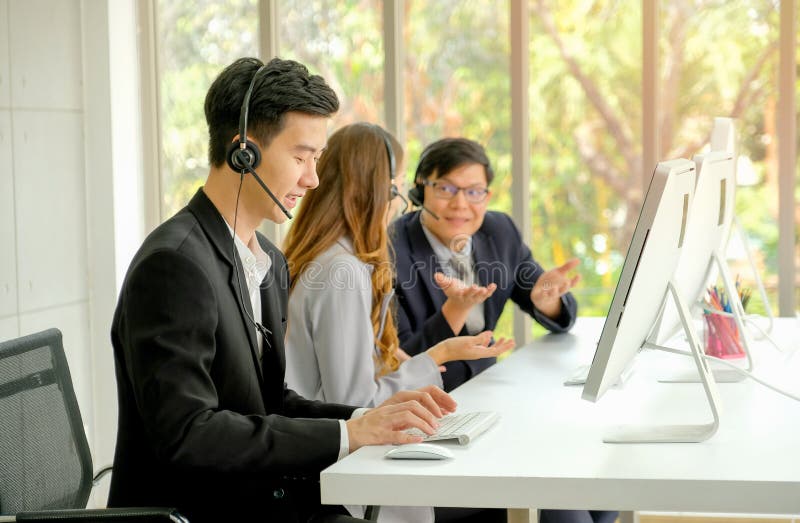 Young man work as operator with diligent habit while his co-workers talking together during working time royalty free stock photo Young man work as operator with diligent habit while his co-workers talking together during working time royalty free stock photo