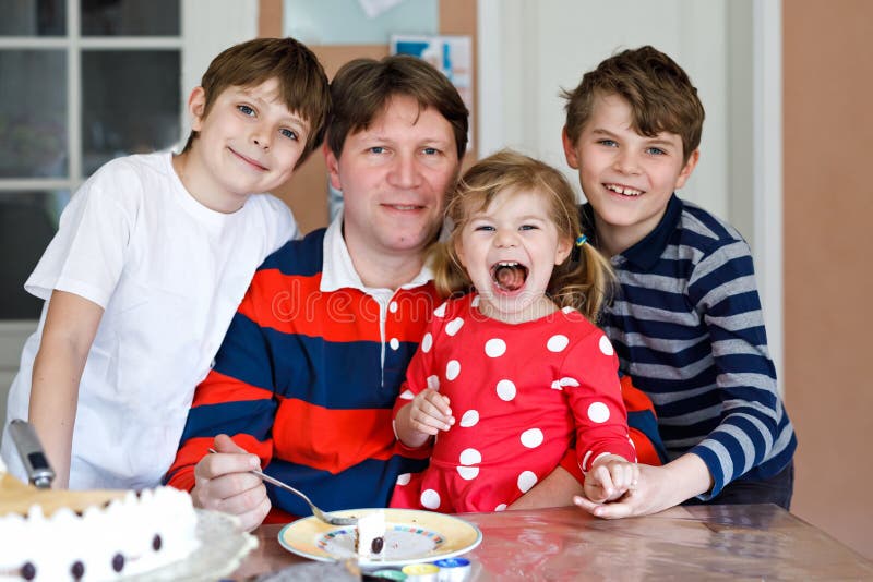 Young middle-aged father with cute little toddler girl daughter and two kids boys sons. Lovely children and dad eating