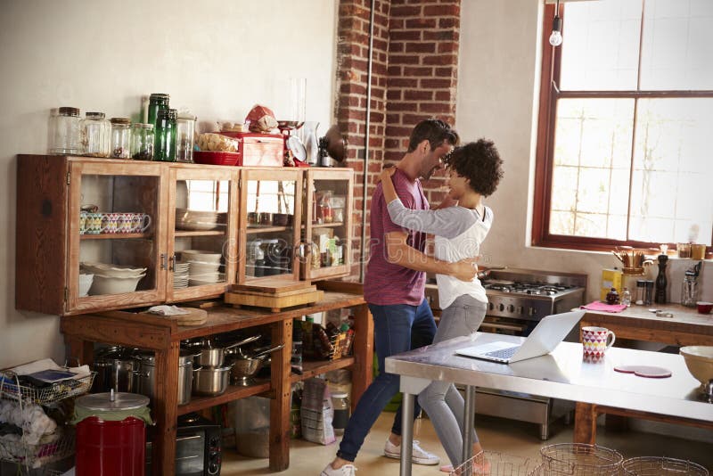 Young mixed race couple dancing in kitchen, full length