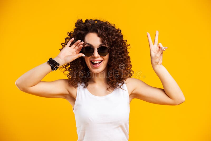 Young woman posing over yellow background. Emotional female portrait. Hipster  girl. Stock Photo