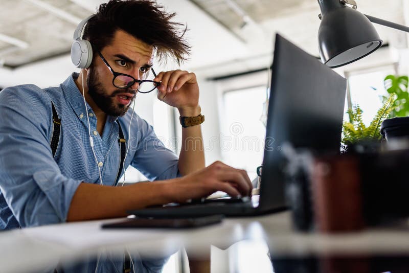 Young bearded businessman is sitting in front of computer, working. Freelancer, entrepreneur works at home. royalty free stock photography Young bearded businessman is sitting in front of computer, working. Freelancer, entrepreneur works at home. royalty free stock photography