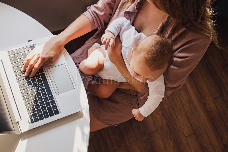 Young mom working remotely on laptop while taking care of her baby.