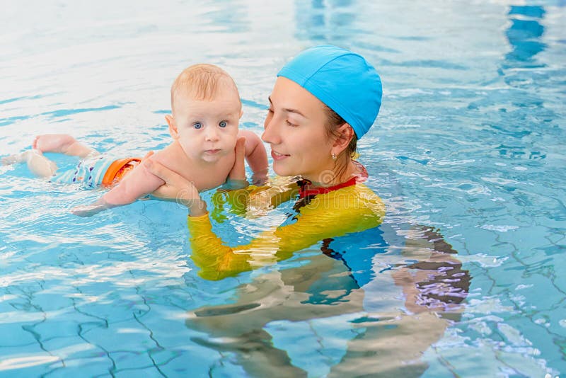 Young mother and baby son are in pool teaches swim