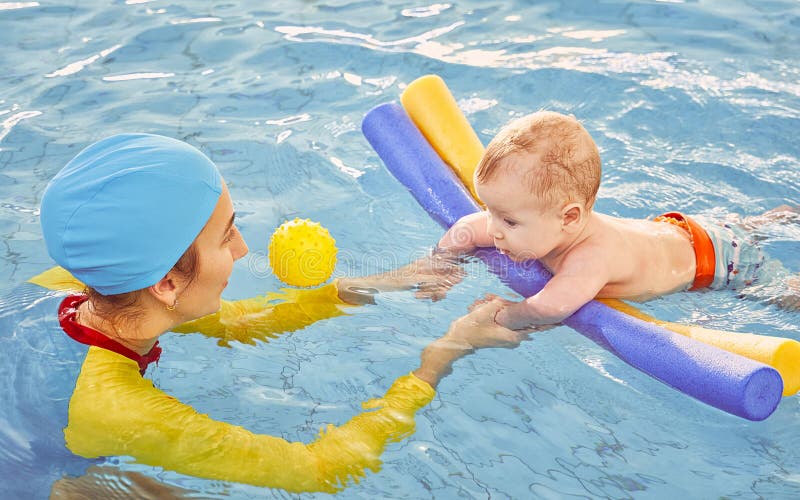 Young mother and baby son are in pool teaches swim