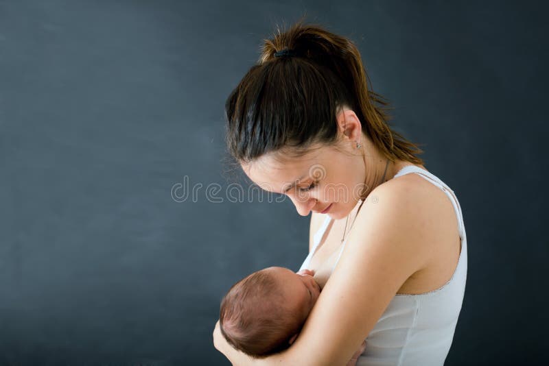 Young mother, breastfeeding her newborn baby boy, tender, care, love, positive emotions. Isolated image, black background, Motherhood concept, family concept