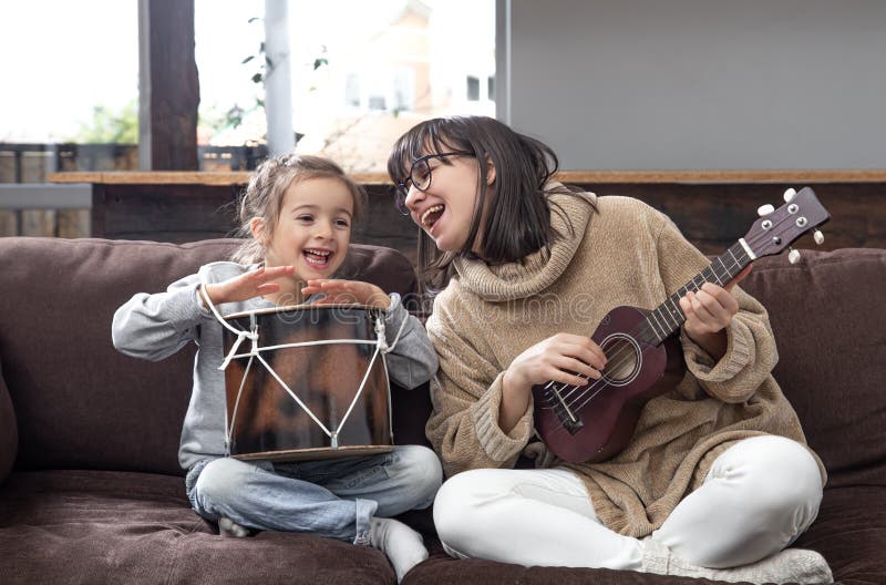 My Daughter Is A Musical Genius Young Mother and Daughter Play Musical Instruments at Home Stock Image