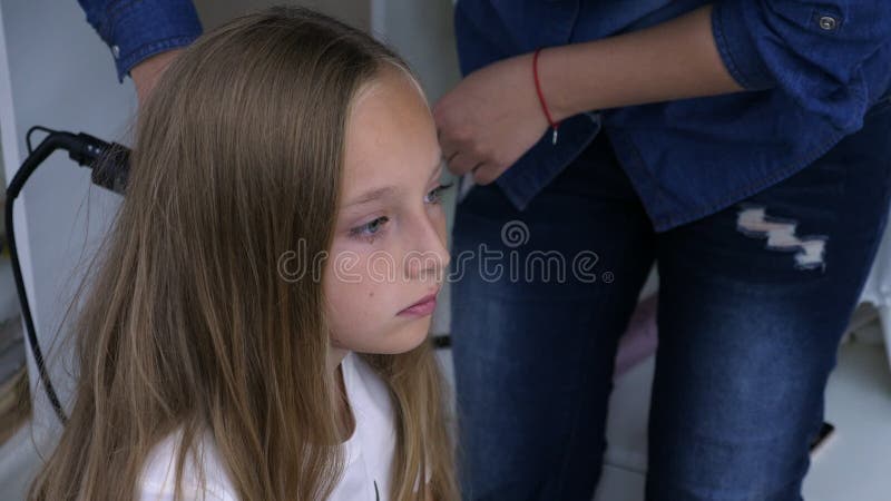 Young mother doing curly hairstyle for long haired teenager girl