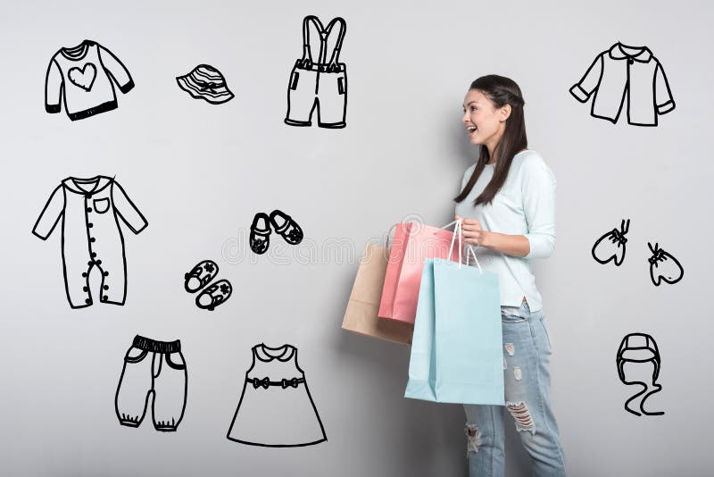 Young mother feeling impressed while buying clothes for her baby stock photos Young mother feeling impressed while buying clothes for her baby stock photos