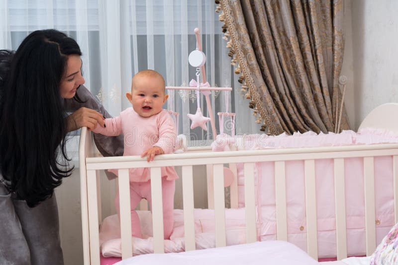 Young mother helping her little daughter stand.