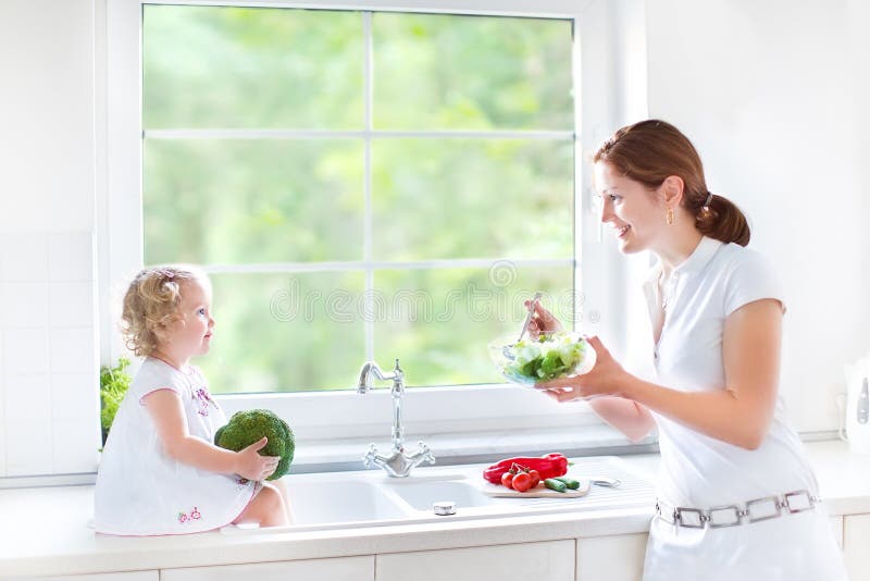 Young mother and her cute toddler daughter cooking royalty free stock photography Young mother and her cute toddler daughter cooking royalty free stock photography