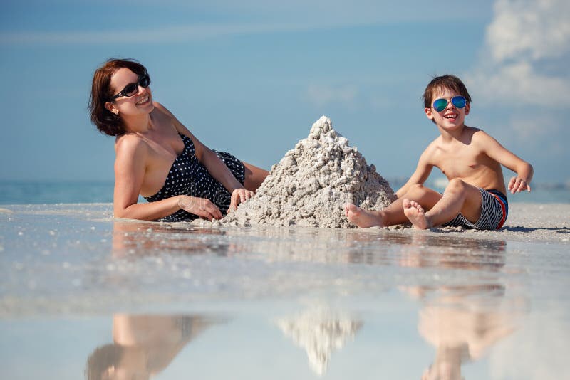 Young mother and her little son building sand