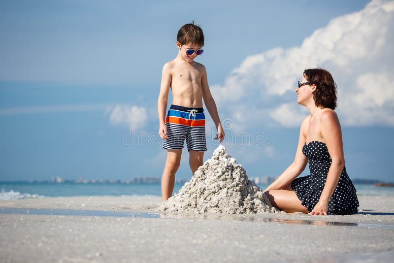 Young mother and her little son building sand castle at beach on Florida