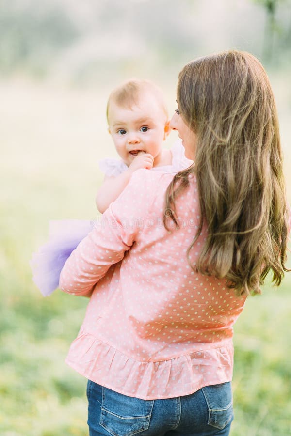 Young mother holding daughter in her arms. Beautiful Mother And Baby outdoors. Nature. Beauty Mum and her Child playing