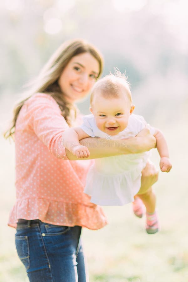 Young mother holding daughter in her arms. Beautiful Mother And Baby outdoors. Nature. Beauty Mum and her Child playing