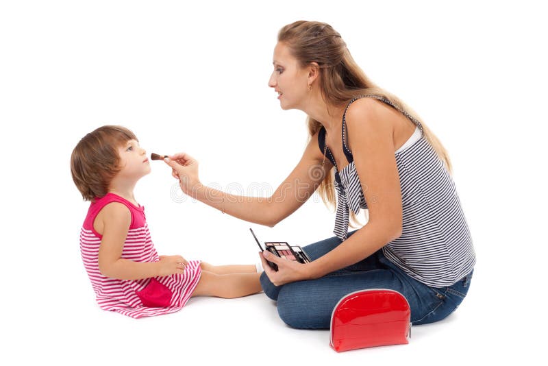 Young mother paints little girl cosmetics