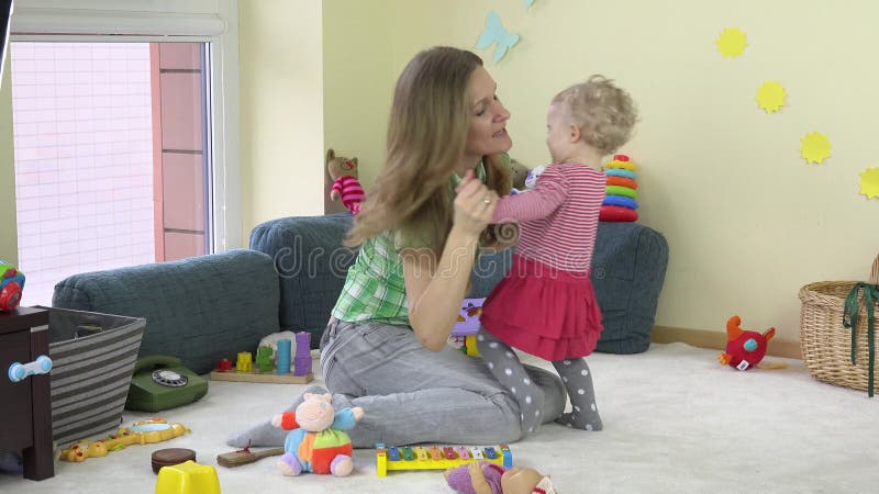 Young mother play dance with little baby daughter in room. 4K