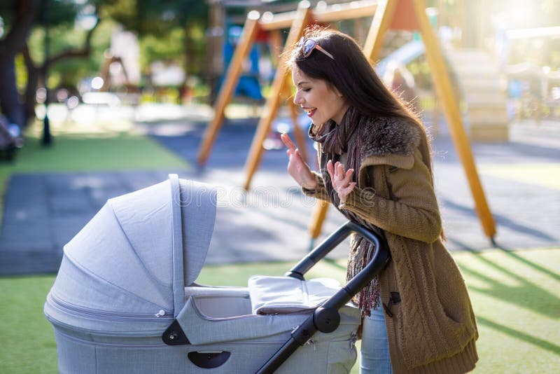 Young mother plays with her newborn baby in the park stock photo Young mother plays with her newborn baby in the park stock photo
