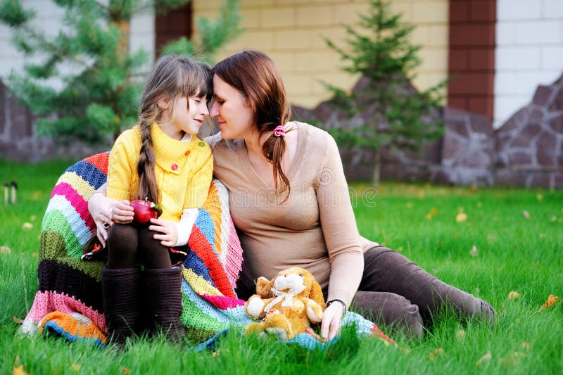 Young mother sitting with daughter on a lawn