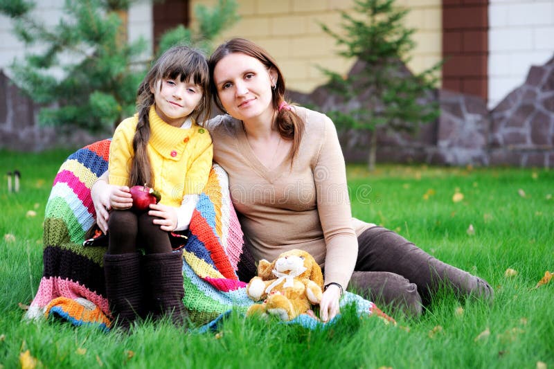 Young mother sitting with daughter on a lawn