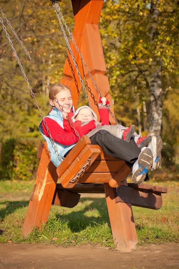 Young mother swinging with dughter in park