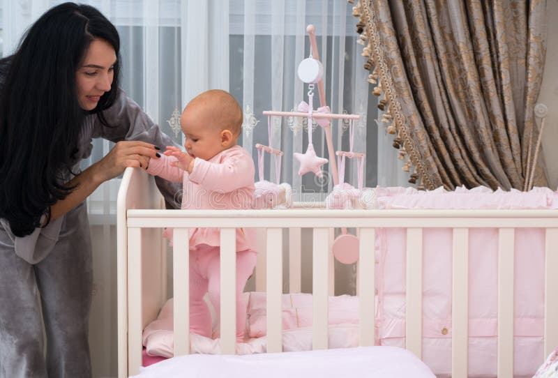 Young mother teaching her daughter to stand.